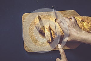 Food concept. Hand cutting bread. Slicing a bread. Top view