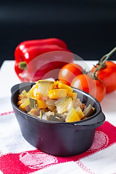 Food concept Homemade French organic Ratatouille in white bake ceramic bowl on blask slate stone board