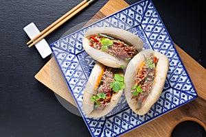 Food concept Homemade organic Pulled Beef Bao Bun or Gua Bao in sqare plate on black background with copy space photo