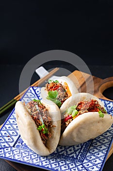 Food concept Homemade organic Pulled Beef Bao Bun or Gua Bao in sqare plate on black background with copy space photo