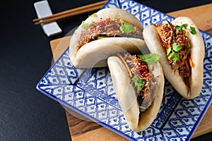 Food concept Homemade organic Pulled Beef Bao Bun or Gua Bao in sqare plate on black background with copy space photo