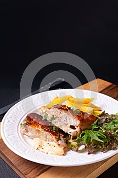 Food concept Homemade Veal cordon bleu with salad and french fried in white ceramic plate on wooden board and black slate stone