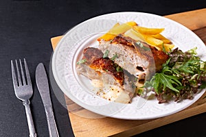 Food concept Homemade Veal cordon bleu with salad and french fried in white ceramic plate on wooden board and black slate stone