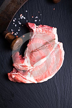 Food concept Organic Fresh pork chop on black slate stone board with vintage chopping knife with copy space