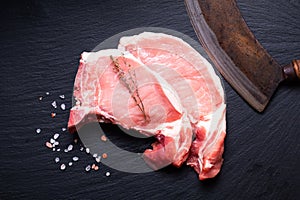 Food concept Organic Fresh pork chop on black slate stone board with vintage chopping knife with copy space