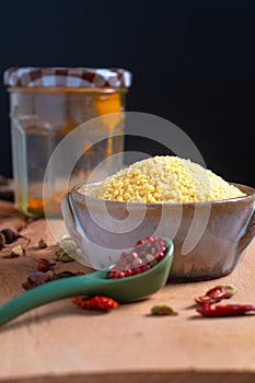 Food concept raw Couscous in brown ceramic bolw and spices on wooden board background