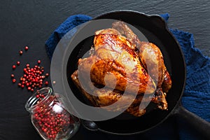 Food concept Roasted, Grilled Whole organic chicken in skillet iron pan on black slate stone board background