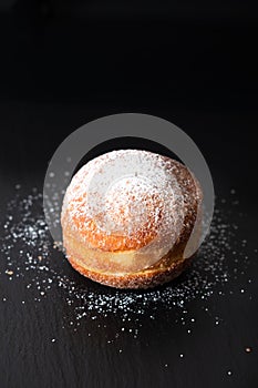 Food concept single Beignet French yeast doughnut deep-fried choux pastry on black slate board background