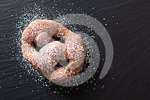 Food concept single Beignet French yeast doughnut deep-fried choux pastry on black slate board background