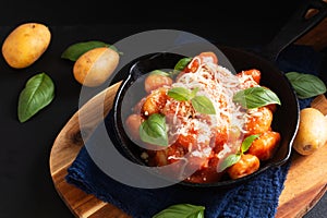 Food concept spot focus homemade gnocchi rosso sauce in skillet iron pan on black background with copy space