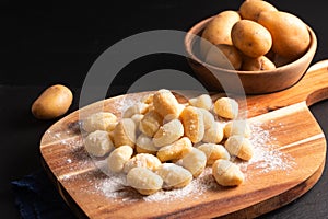 Food concept Spot focus homemade gnocchi on wooden board on black background with copy space