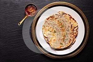 Food concept spot focus homemade Paratha, Parotta or Porotta layered flatbread  on black background with copy space