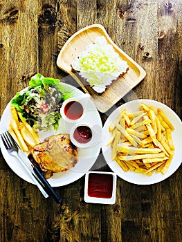 Top view of grilled chicken steak, french fries or potato fries with ketchup and melon fruit toast on wooden table