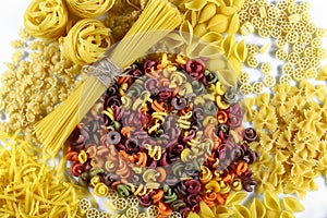 Food concept - various uncooked, raw Italian pasta on white background, top view, set