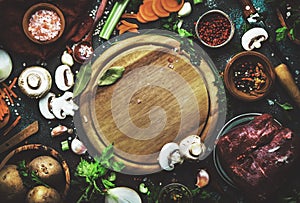 Food cooking background. Fresh organic vegetables, ingredients, spices and meat for warm autumn soup on vintage kitchen table with