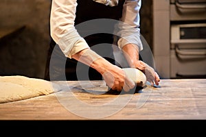 Baker portioning dough with bench cutter at bakery