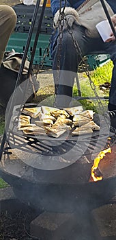 food cooking on a campfire over flamng logs of wood