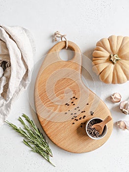 Food cooking concept. Beige pumpkin on wood cutting board layout, herbs and spices on the kitchen table. Top view. Copy space