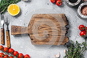 Food cooking and healthy eating background with wooden cutting board and fresh seasoning, herbs and vegetables. Gray