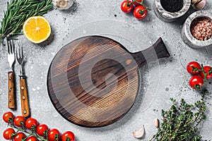 Food cooking and healthy eating background with wooden cutting board and fresh seasoning, herbs and vegetables. Gray