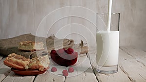 Food, dairy products with raspberries, milk or yogurt are poured into a transparent glass on wooden boards