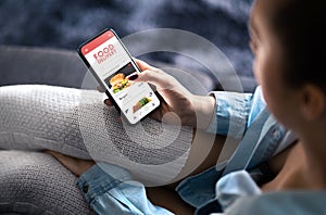 Food delivery app in mobile phone. Restaurant order online. Woman using smartphone to get take away lunch home delivered.