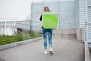 Food delivery concept. The food delivery woman has a green fridge backpack. She wants to deliver faster and get to