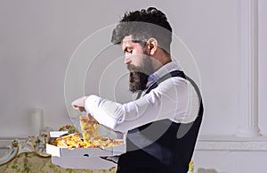 Food delivery concept. Man with beard and mustache holds box with tasty fresh hot pizza. Macho in classic clothes hungry