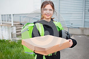 Food delivery concept. The Pizza delivery woman has a green fridge backpack. She wants to deliver faster and get to