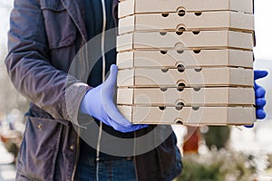 Food delivery courier in medical gloves with many boxes of pizza. Stay at home because coronavirus covid 19 killing
