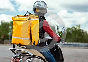 Food Delivery Courier With Yellow Backpack Riding Motorbike Outdoors, Rear-View photo