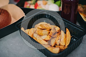 Food delivery lunch.Fried Crinkle French fries potatoes in a pan. Black Wooden background. Top view