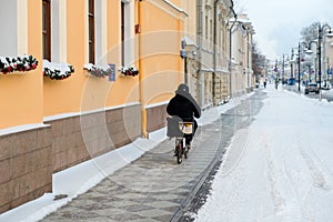 Food delivery man on bicycle working at winter on dirty city street