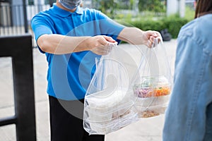 Food Delivery man wearing mask handing plastic bags shopping online from supermarket to female client