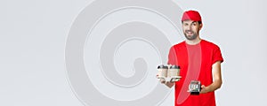 Food delivery, quarantine, stay home and order online concept. Cheeky courier in red uniform cap and t-shirt, wink to