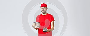 Food delivery, quarantine, stay home and order online concept. Cheeky courier in red uniform cap and t-shirt, wink to