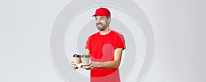 Food delivery, quarantine, stay home and order online concept. Friendly courier in red uniform cap and t-shirt, handing