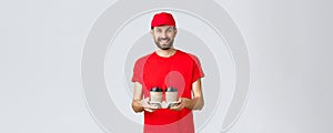 Food delivery, quarantine, stay home and order online concept. Smiling courier in red cap and t-shirt bring coffee to