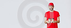 Food delivery, quarantine, stay home and order online concept. Smiling courier in red cap and t-shirt bring coffee to