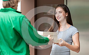 A food delivery rider on a motorcycle arrives at the customer`s place and waits for delivering an order for a client. She comes