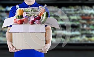 Food delivery service for order online grocery shopping concept. Delivery man in blue uniform hand holding paper box package.