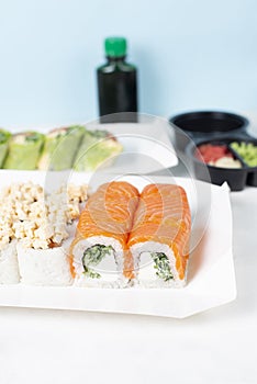 Food delivery takeaway concept. Lunch box with sushi set. Assorted sushi Philadelphia roll cheese with squid on white light