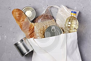 Food delivery.Textile shopping bag with food supplies on a gray concrete background. Rice, buckwheat, pasta, bread