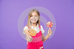 Food and dessert. Girl smile with lollipops on violet background. Happy kid with swirl caramels on purple background