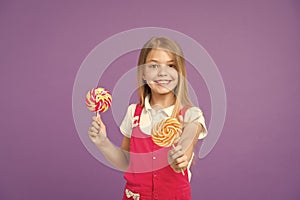 Food and dessert. Girl smile with lollipops on violet background. Happy kid with swirl caramels on purple background