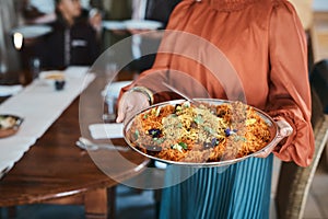 Food, dinner and consumables with a traditional paella dish in the hands of a woman at home. Closeup of a bowl of