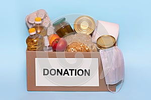 Food in a donation cardboard box, isolated on blue background,copy space. Coronavirus Relief Funds and Donations.Charity donations