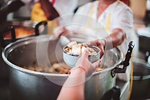 Food donation to hungry people, poor hands waiting to receive free food from volunteers