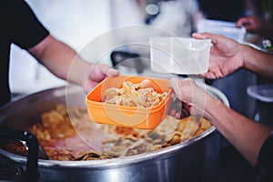 Food donation to hungry people, poor hands waiting to receive free food from volunteers