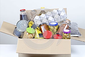 Food donations box with grocery products on white table